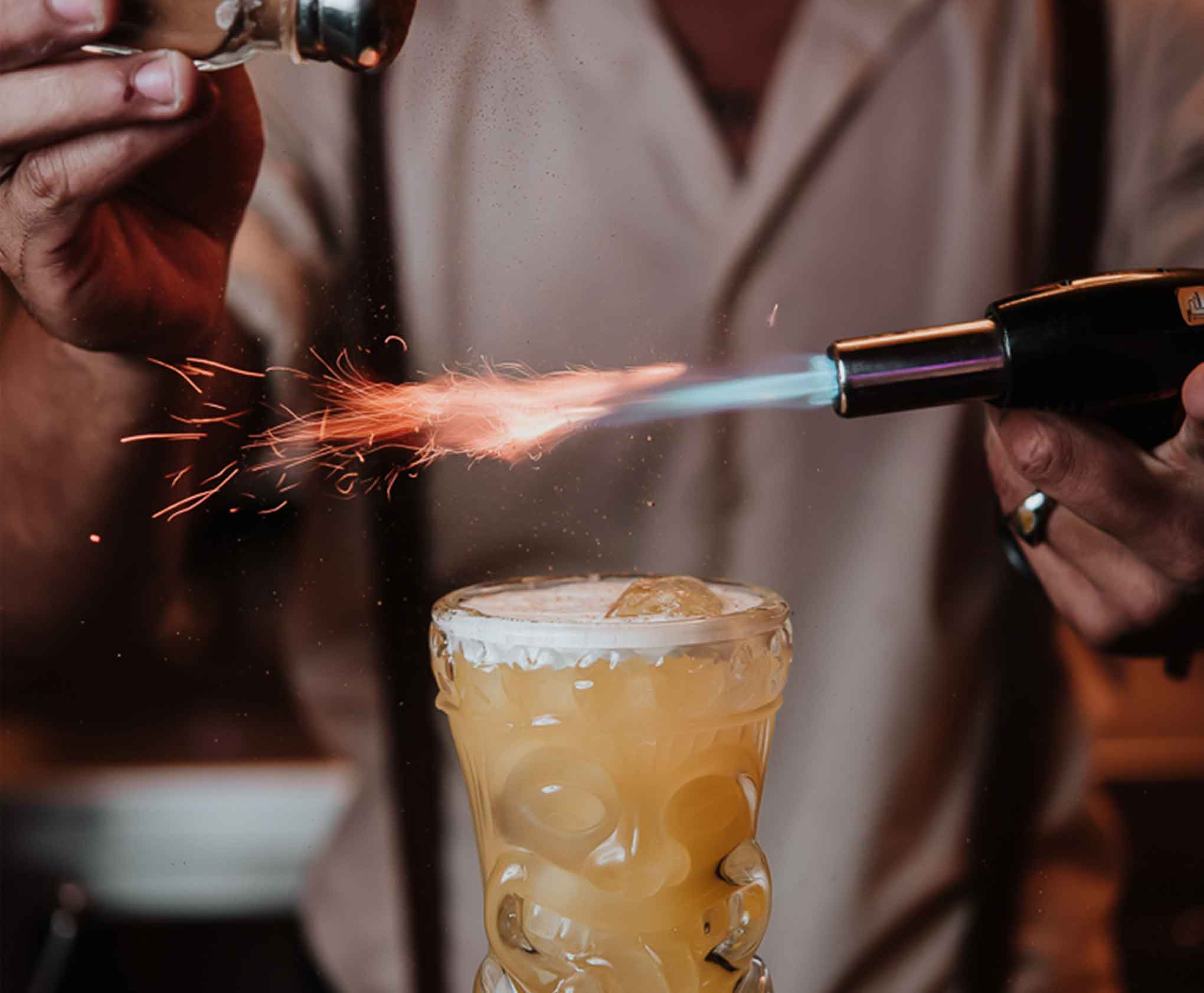 Coctelero decorando cóctel con una pistola de encendido en Café en Meloneras